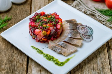 Beyaz bir tabakta ringa balıklı salata.