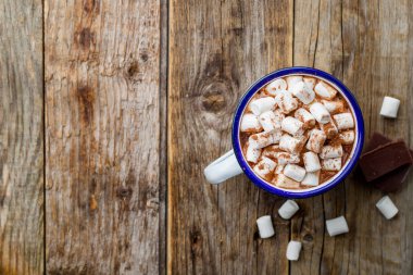 Eski ahşap arka planda lokum olan demir bardakta sıcak çikolata. Boşluğu kopyala, üst görünüm