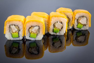 Erimiş peynirli suşi rulosu, siyah üzerine yansımalı.