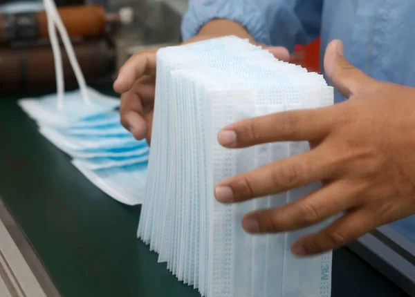 Factory workers are producing masks for protection against viruses.