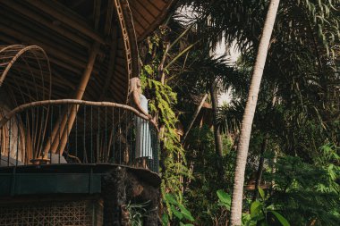 Ormandaki bambu bir evin balkonunda sarışın.