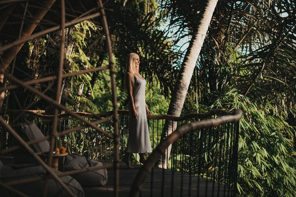 Blond op balkon van een bamboe huis in de jungle — Stockfoto