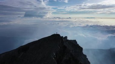 Bir adam bir dağın tepesinde ya da bir volkan 4k drone 'unda duruyor. Patlama. krater