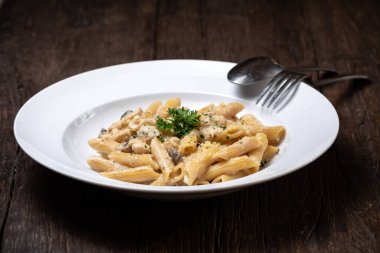 Beyaz mantarlı makarna koyu ahşap masada kremalı soslu porcini.