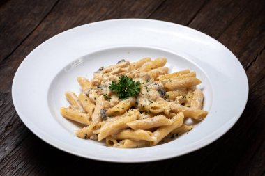 Beyaz mantarlı makarna koyu ahşap masada kremalı soslu porcini.