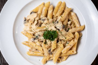 Beyaz mantarlı makarna koyu ahşap masada kremalı soslu porcini.