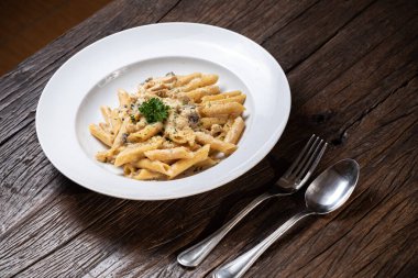 Beyaz mantarlı makarna koyu ahşap masada kremalı soslu porcini.