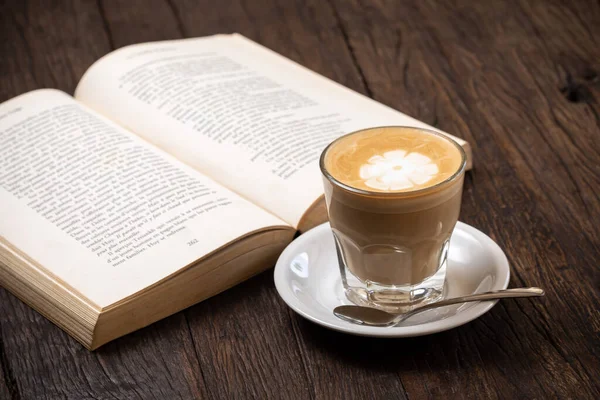 Filiżanka kawy cappuccino gorące latte lub kawa z mlekiem w szklanej filiżance, otwarta książka — Zdjęcie stockowe