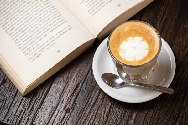 Kaffeetasse Cappuccino oder Kaffee mit Milch im Glas, aufgeschlagenes Buch — Stockfoto