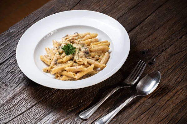 Beyaz mantarlı makarna koyu ahşap masada kremalı soslu porcini.