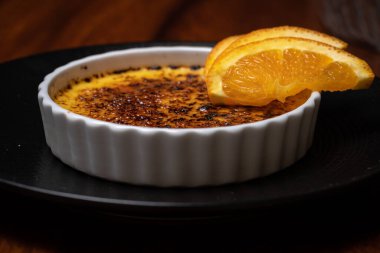 Krem karamel, koyu ahşap masada portakallı yanmış krema..