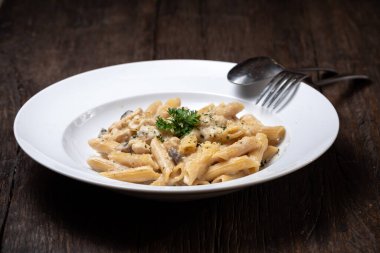 Beyaz mantarlı makarna koyu ahşap masada kremalı soslu porcini.