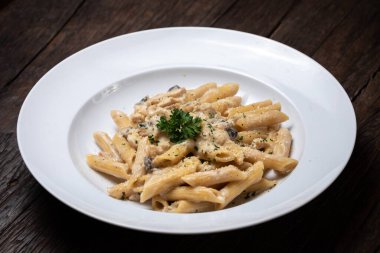 Beyaz mantarlı makarna koyu ahşap masada kremalı soslu porcini.