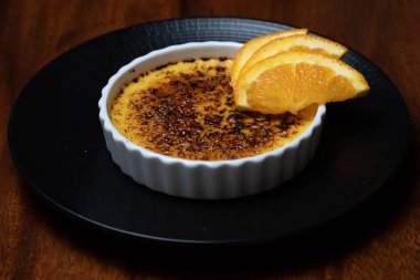 Krem karamel, koyu ahşap masada portakallı yanmış krema..
