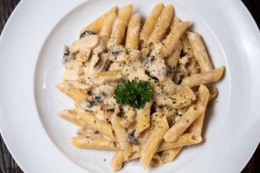 Beyaz mantarlı makarna koyu ahşap masada kremalı soslu porcini.