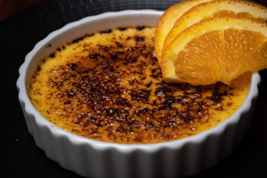 Krem karamel, koyu ahşap masada portakallı yanmış krema..