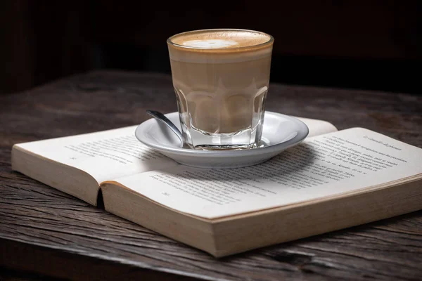 Xícara de café cappuccino quente latte ou café com leite em uma xícara de vidro, livro aberto — Fotografia de Stock