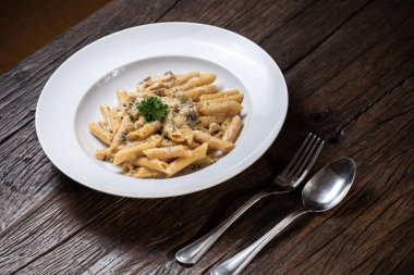 Beyaz mantarlı makarna koyu ahşap masada kremalı soslu porcini.