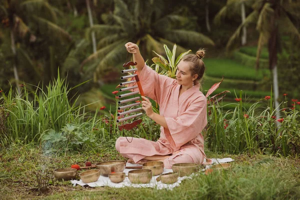 Pembe kimonolu sarışın kadın meditasyon yapan Himalaya Tibet müziğiyle oynuyor. 