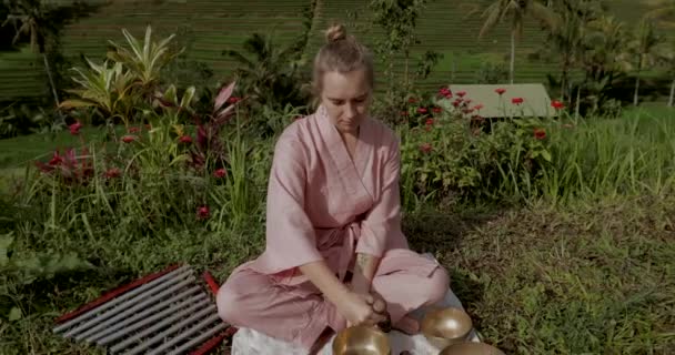 Donna bionda in kimono rosa che gioca su una ciotola di canto Himalayana meditativa. — Video Stock