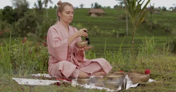 穿着粉色和服、白发苍苍的年轻女子在一只歌唱的碗上玩耍 — 图库视频影像