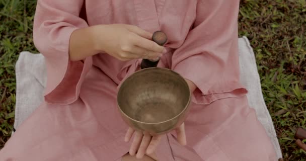 Молодая женщина с белыми волосами в розовом кимоно играет на поющей чаше — стоковое видео