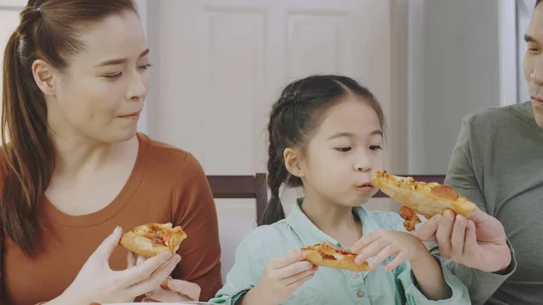 Aile Asyalı insanlar evde lezzetli pizzaların tadını çıkarmaktan mutlu olurlar. Anne-baba ve kızı paket servis servisinden lezzetli İtalyan yemekleri yiyorlar. Yemek siparişini kabul et.