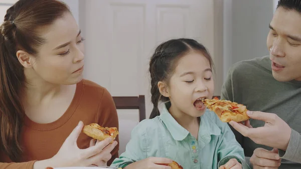 Aile Asyalı insanlar evde lezzetli pizzaların tadını çıkarmaktan mutlu olurlar. Anne-baba ve kızı paket servis servisinden lezzetli İtalyan yemekleri yiyorlar. Yemek siparişini kabul et.