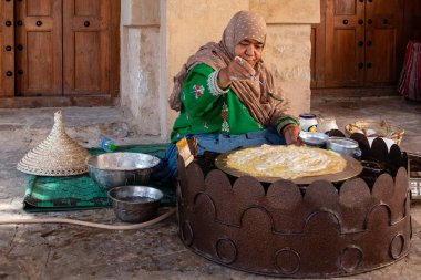 Nizwa, Umman - 23 Kasım 2019 Geleneksel elbiseli kadın Nizwa 'nın kalesinde çıtır bir krep hazırlıyor.