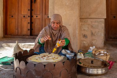 Nizwa, Umman - 23 Kasım 2019 Geleneksel elbiseli kadın Nizwa 'nın kalesinde çıtır bir krep hazırlıyor.