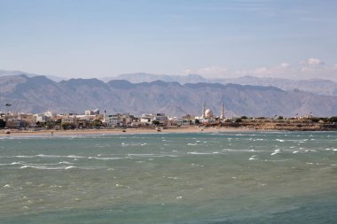 Panoramik kıyı şeridi manzaralı Sur, Oman 'ın arka planında dağlar var.