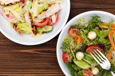 Çekici bir arkaplana yerleştirilmiş sosla karıştırılmış taze salata içerikli beyaz tabaklar. Menü, pankart veya reklam için bir yer