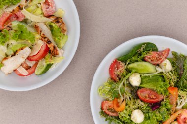 Çekici bir arkaplana yerleştirilmiş sosla karıştırılmış taze salata içerikli beyaz tabaklar. Menü, pankart veya reklam için bir yer