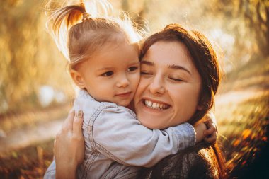 Parkta annesini kucaklayan kız, sonbahar parkında bir hafta sonu yürüyüşü yapıyor. seçici odak, gürültü etkisi,