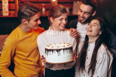 Arkadaşları tarafından doğum gününde verilen pastayı tutan genç ve güzel bir sarışın. En iyi arkadaşlarından oluşan bir grup, doğum gününde kızı tebrik etmek için geldi.