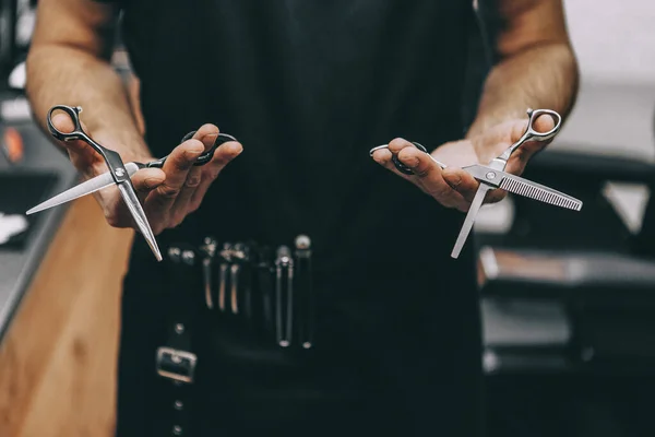 stock image professional barber tool: sharpened scissors held by a haircut master in a modern barber shop. A concept for barbershops, beauty salons and hairdressers