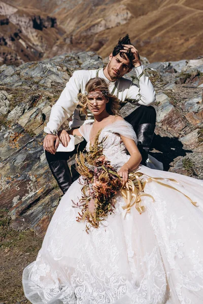 young, stylish, loving brides posing for a photo on an incredibly beautiful background of the Caucasus Mountains: hugging, kissing, laughing, and rejoicing in the happiest day of their lives