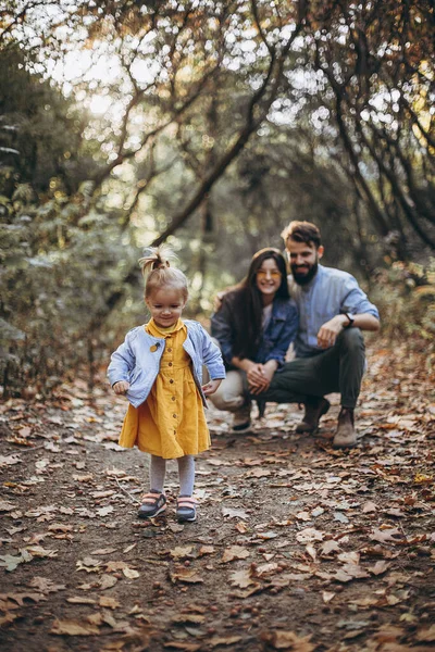 幸せな若い家族 スタイリッシュなお父さん 美しいお母さんと甘い小さな娘は一緒に一日を過ごし 子供は日没時に自然の中で走っています 選択的焦点ノイズ効果 — ストック写真