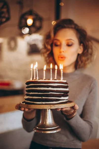 年轻迷人的金发姑娘带着华丽的模特微笑捧着蛋糕 一个快乐的生日女孩在意想不到的礼物中的情感 自制的蛋糕 点着蜡烛 有选择性地聚焦 噪音效果 — 图库照片