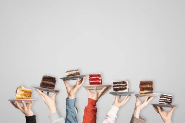 Kafe veya pastane için tatlı kavramı: insanların elinde farklı kekler olan tabaklar, metinleriniz için yer