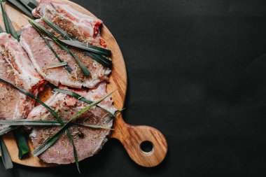 Çiğ et, baharat, biberiye, kekik ve salamura şeklinde bir kesme tahtasına uzan. Arka planda fotokopi alanı, üst görünüm. Et marine etme kavramı