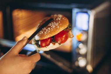 Bir fast-food kafede mikrodalga fırında sandviç yapmak ya da ızgara yapmak.