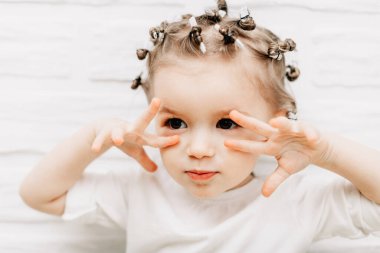 Parlak bebek duyguları olan bir kızın portresi. Küçük kıvırcık kız fotoğraf için poz veriyor.