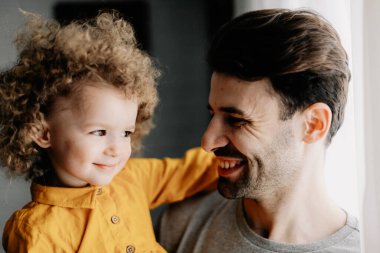 Baba ve kızı. Genç ve güzel babası ve küçük kıvırcık kızı evde sarılıp eğleniyorlar.