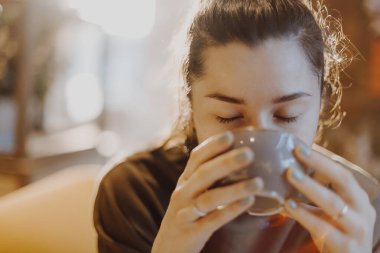 Pencerenin yanındaki kafede kahve içen genç ve tatlı bir kız.