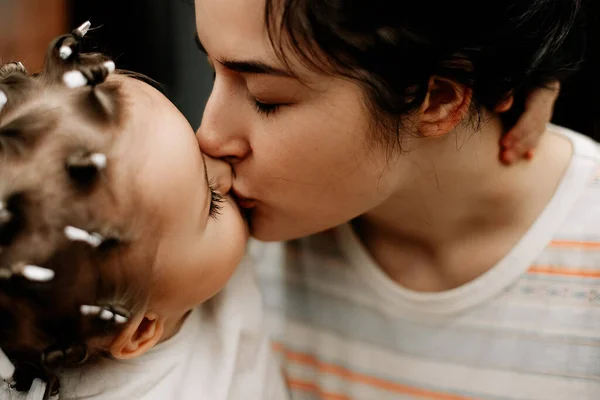 ママは娘と抱き合ってキスする 手作りのカールで頭をカールしている子供の肖像画 — ストック写真