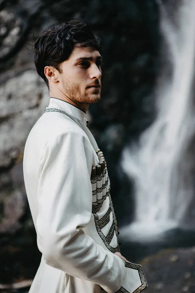 ノイズ効果 選択的フォーカス スタイリッシュなグルジアの男は白い国民の男性のスーツを着た コーカサス山脈での結婚式中のグルジア新郎の肖像 — ストック写真