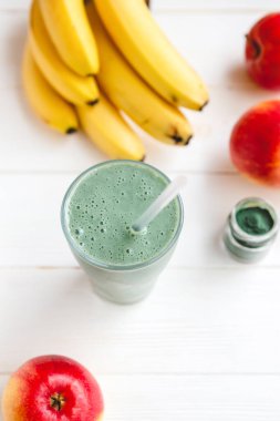 Sağlıklı bir işletme için meyve kokteylinin tanıtım çekimi. Fotoğrafta, meyve ve alg spirulinasından yapılmış yeşil bir içecek bardağı var.