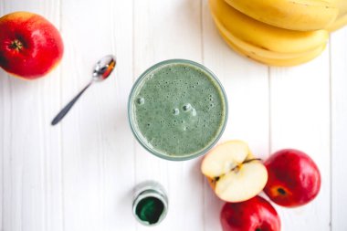 Sağlıklı bir işletme için meyve kokteylinin tanıtım çekimi. Fotoğrafta, meyve ve alg spirulinasından yapılmış yeşil bir içecek bardağı var.