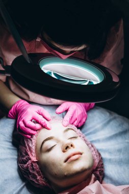 Müşterinin portresi, büyüteç kaplıcasının altındaki yüzü. Gerçek doğal güzelliğe sahip bir kadın, doktoruyla düzenli estetik ameliyatta olan genç bir esmer.